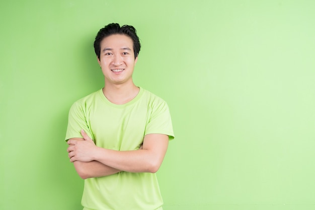 Portrait d'un homme asiatique en t-shirt vert posant sur vert