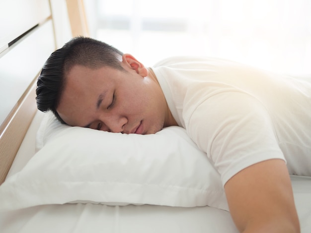 Photo portrait d'un homme d'asie fatigué de dormir dans le lit à la maison