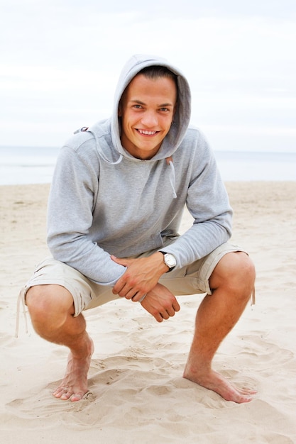 Portrait d'homme assis posant sur la plage