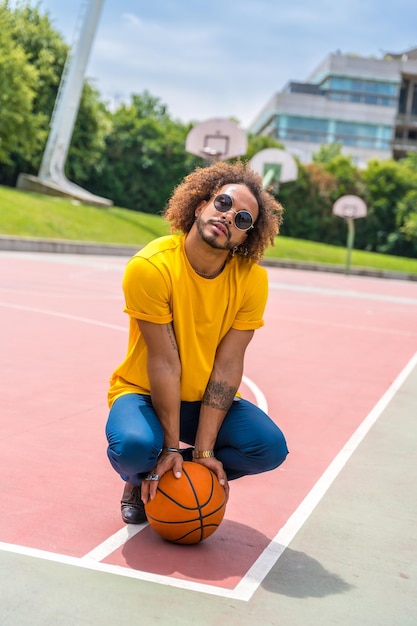 Portrait d'un homme aux cheveux afro dans un t-shirt jaune avec un portrait de ballon de basket dans la ville