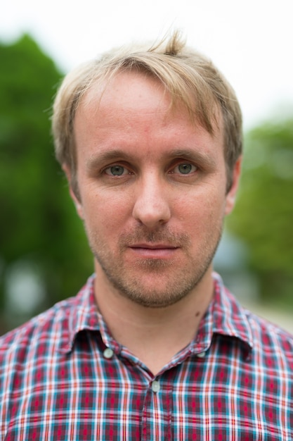 Portrait d'homme aux cheveux blonds se détendre à l'extérieur