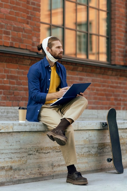 Portrait d'un homme avec un bandage d'oreille dessinant sur un bloc-notes à l'extérieur