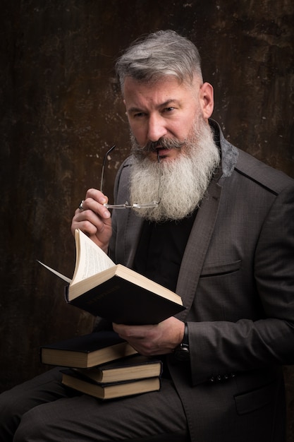 Portrait d'un homme barbu aux cheveux gris avec des lunettes de lecture livre