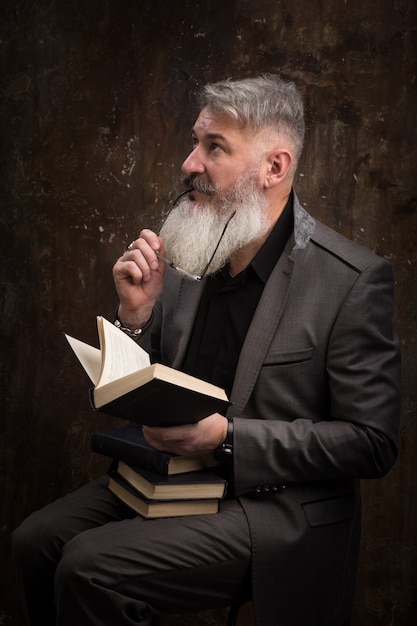 Portrait d'un homme barbu aux cheveux gris avec des lunettes de lecture livre