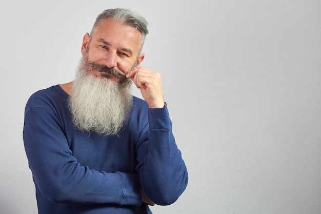 Portrait d'homme barbu aux cheveux gris mature en sweat bleu