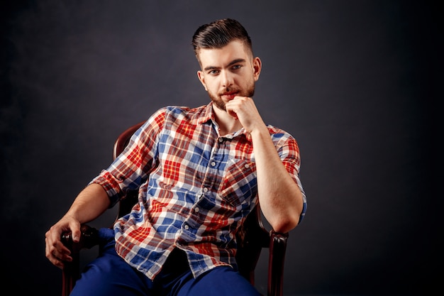 Portrait d'homme barbu aux cheveux longs sur fond sombre.