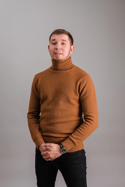 Portrait d'un homme barbu dans un chandail rouge debout sur un fond gris