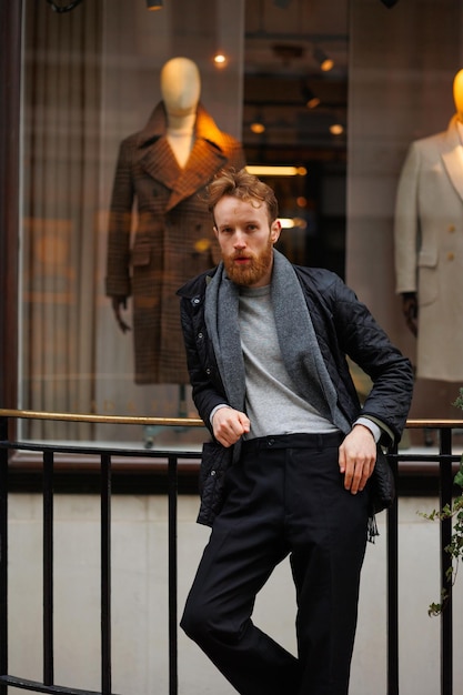 Portrait d'un homme barbu élégant sur fond de vitrine de magasin de vêtements élégants