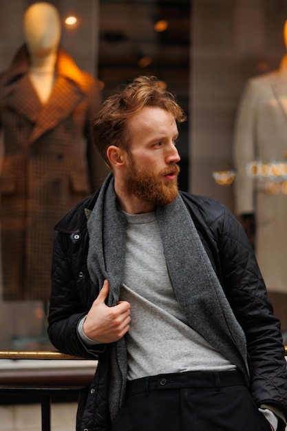 Portrait d'un homme barbu élégant sur fond de vitrine de magasin de vêtements élégants