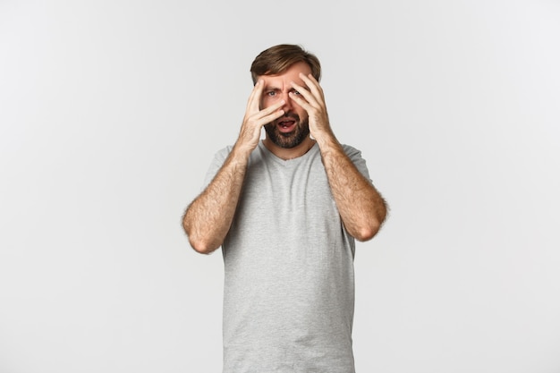 Portrait d'homme barbu embarrassé en t-shirt gris