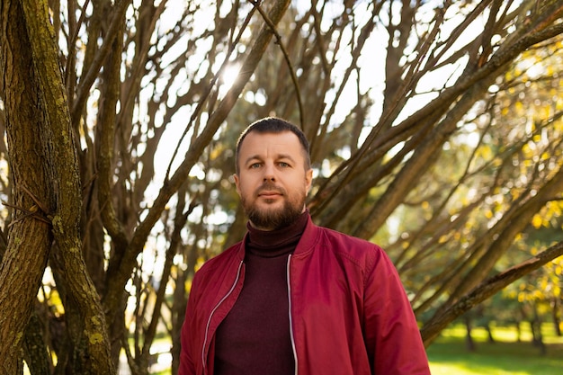 Portrait d'un homme barbu fort dans une veste rouge en parc d'automne