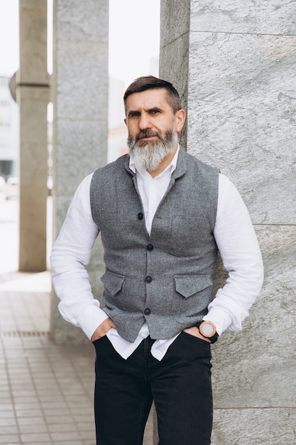 Portrait d'un homme barbu gris et brutal passant du temps sur la scène urbaine