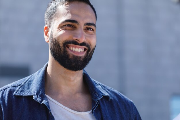 Portrait d'un homme barbu joyeux et réussi, debout à l'extérieur