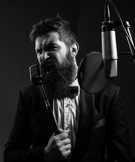 Portrait d'un homme barbu avec un microphone chantant un musicien dans une salle de musique un type drôle chantant dans