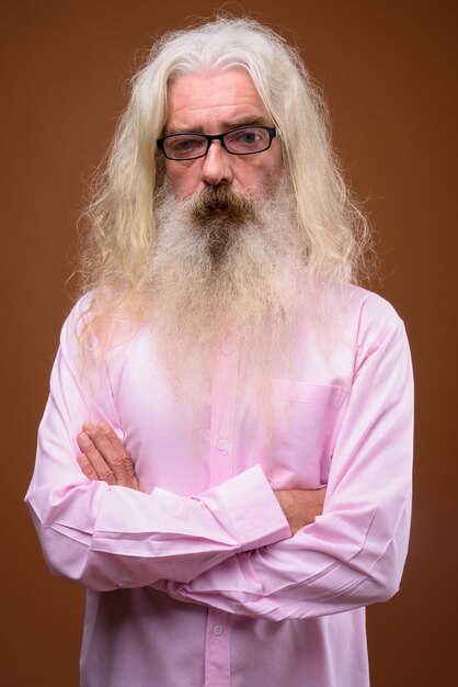 Portrait d'homme barbu senior portant une chemise rose
