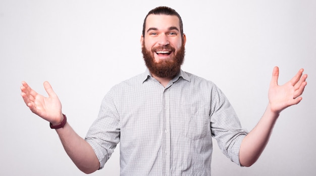 Portrait d'un homme barbu souriant à la caméra et tenant ses deux mains montrant qu'il veut un câlin