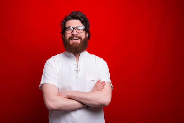 Portrait d'homme barbu souriant heureux avec les bras croisés à confiant à l'appareil photo