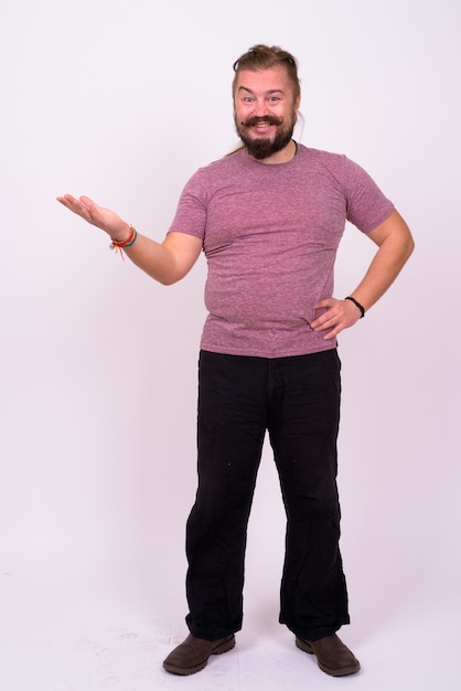 Portrait d'homme barbu en surpoids avec moustache et cheveux longs contre le mur blanc