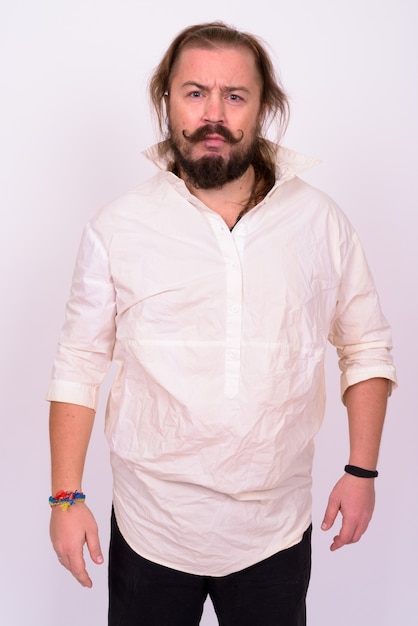 Portrait d'homme barbu en surpoids avec moustache et cheveux longs portant une chemise blanche contre le mur blanc