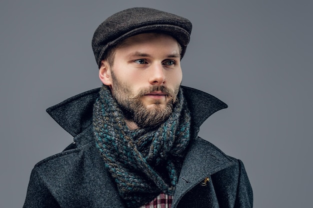 Portrait d'un homme barbu vêtu d'une veste de ver et d'un bonnet de laine isolé sur fond gris.