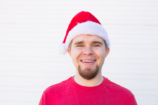 Portrait d'un homme beau drôle en bonnet de Noel s'amuser sur blanc