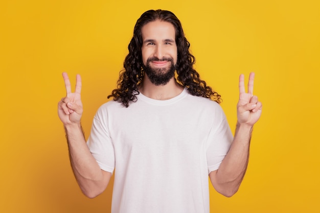 Portrait d'un homme beau et positif drôle montrant un signe v sur fond jaune