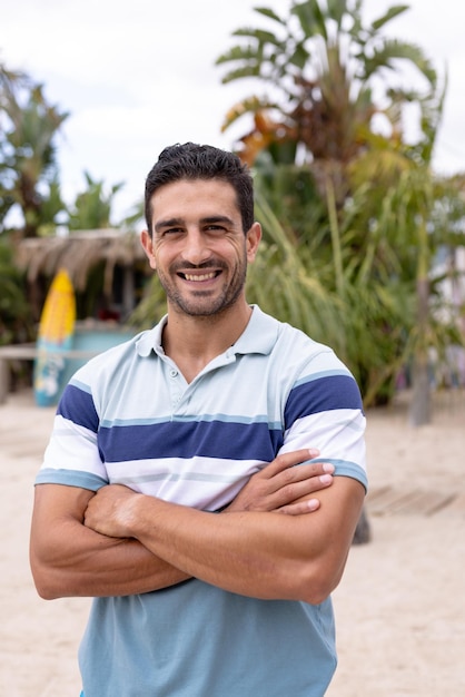 Portrait d'un homme biracial heureux regardant la caméra et souriant à la plage, avec espace de copie. Passer du temps de qualité, style de vie, été et concept de vacances.