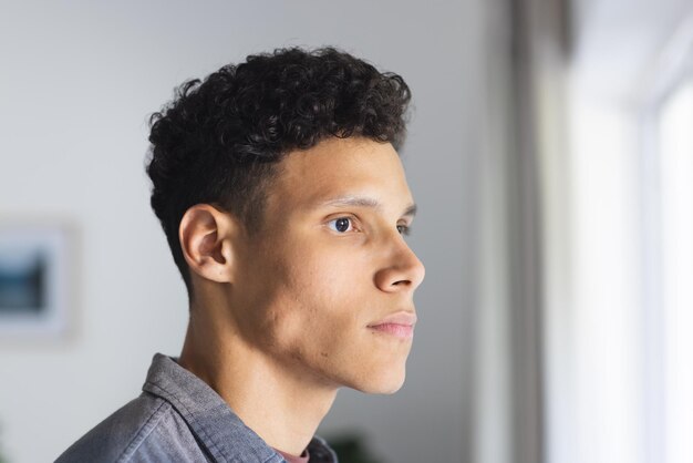 Photo portrait d'un homme biracial sérieux regardant le côté dans le salon à l'espace de copie à la maison