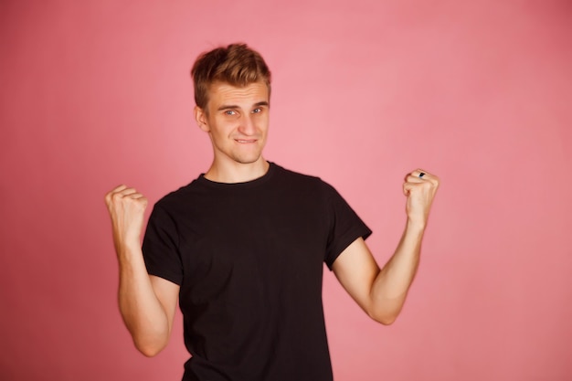 Portrait d'homme blanc en t-shirt noir dans une pose réussie. Le geste de l'homme dit OUI, et est destiné à gagner. Homme fort qui crie, tenant ses mains dans ses poings