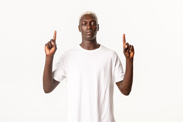 Portrait d'homme blond afro-américain assertif sérieux, à la confiance et pointant les doigts vers le haut