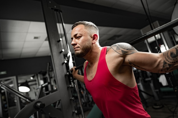 Portrait d'homme bodybuilder en chemise rouge dans la salle de sport