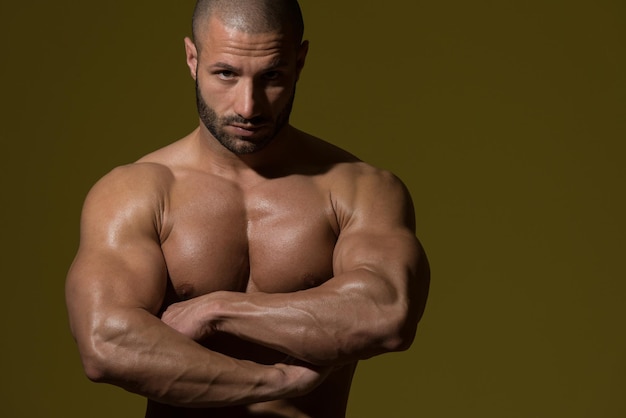 Portrait d'un homme en bonne forme physique montrant son corps bien formé dans une pièce sombre