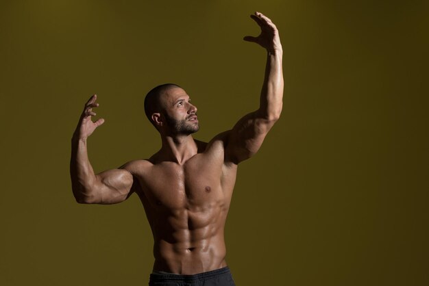 Portrait d'un homme en bonne forme physique montrant son corps bien formé dans une pièce sombre