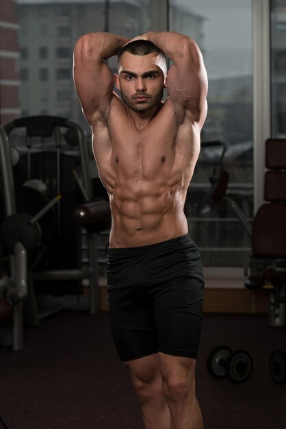 Portrait d'un homme en bonne forme physique montrant son corps bien formé dans la salle de sport