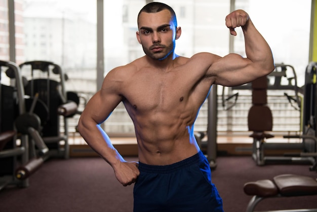 Portrait d'un homme en bonne forme physique montrant son corps bien formé dans la salle de sport