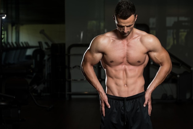 Portrait d'un homme en bonne forme physique posant dans une salle de sport moderne