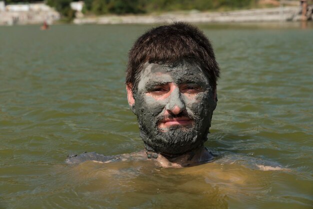 Photo portrait d'un homme avec de la boue sur le visage dans un lac