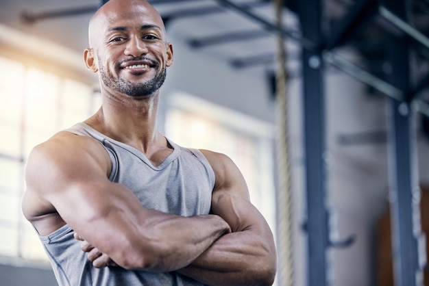 Portrait d'homme et bras croisés dans la salle de sport pour l'exercice avec l'entraînement au sourire ou l'exercice pour la forme physique Personne masculine confiante ou entraîneur personnel dans un club de sport ou un cardio ou un bien-être fort à Chicago