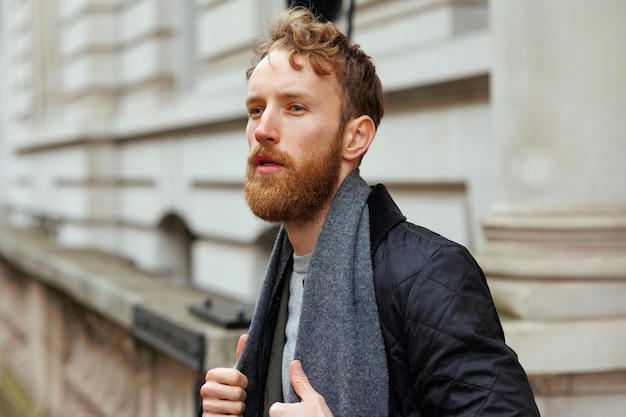 Portrait d'un homme brutal élégant avec une barbe posant dans une rue de la ville