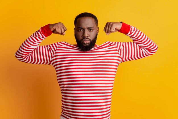 Portrait d'un homme brutal et fort montre de gros biceps musculaires posant sur fond jaune