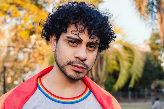 Portrait d'un homme caucasien à l'extérieur avec un drapeau de la fierté gay regardant la caméra