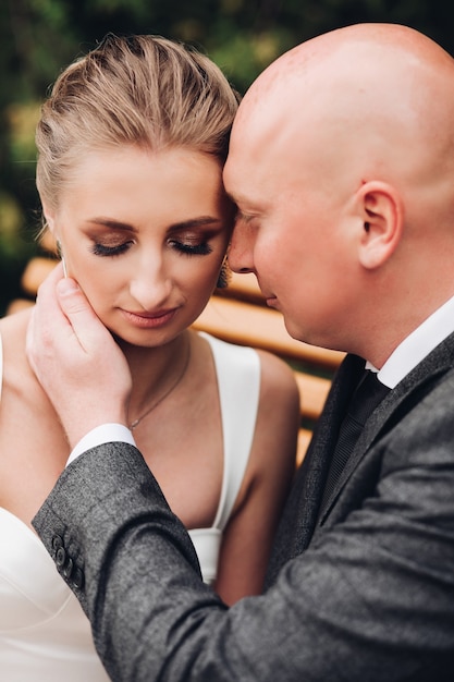 Portrait d'un homme caucasien fort avec sa belle femme en robe blanche veulent s'embrasser