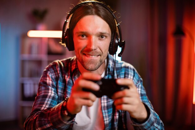 Portrait d'un homme caucasien joyeux dans un casque à l'aide d'une console à distance pour jouer à des jeux vidéo à la maison