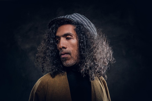 Portrait d'un homme charismatique d'âge moyen en manteau marron au studio photo sombre.