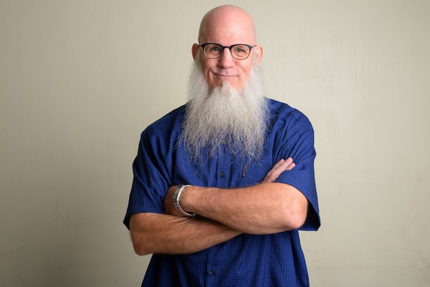 Portrait d'homme chauve mature avec une longue barbe grise contre un mur blanc