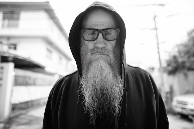 Portrait d'homme chauve mature avec une longue barbe grise dans les rues à l'extérieur en noir et blanc