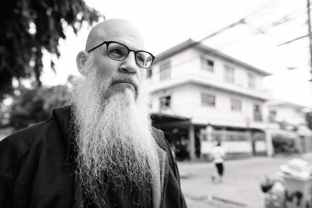 Portrait d'homme chauve mature avec une longue barbe grise dans les rues à l'extérieur en noir et blanc