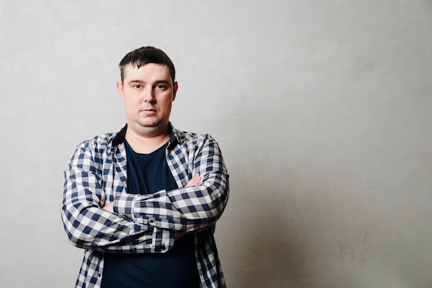 Photo portrait d'un homme en chemise contre un mur gris