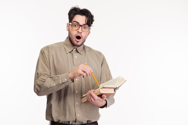 Portrait d'un homme choqué debout avec un livre isolé sur un mur blanc