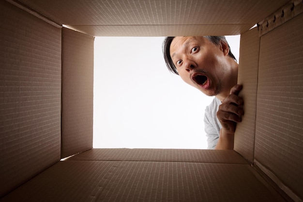 Portrait d'un homme choqué regardant dans une boîte en carton